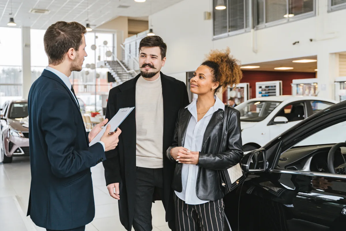 Couple discussing car financing with a dealer inside a showroom