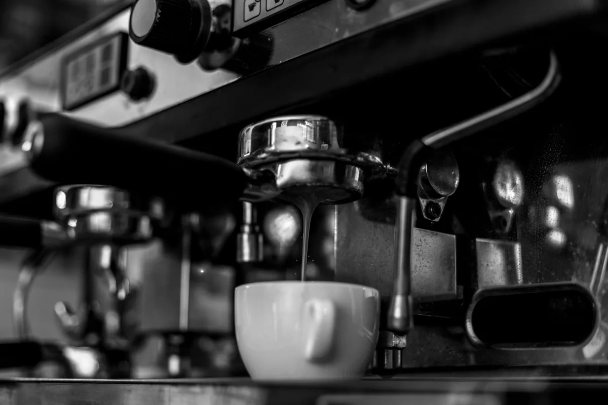 Black and white close-up of an espresso machine brewing coffee into a ceramic cup — best coffee makers 2026