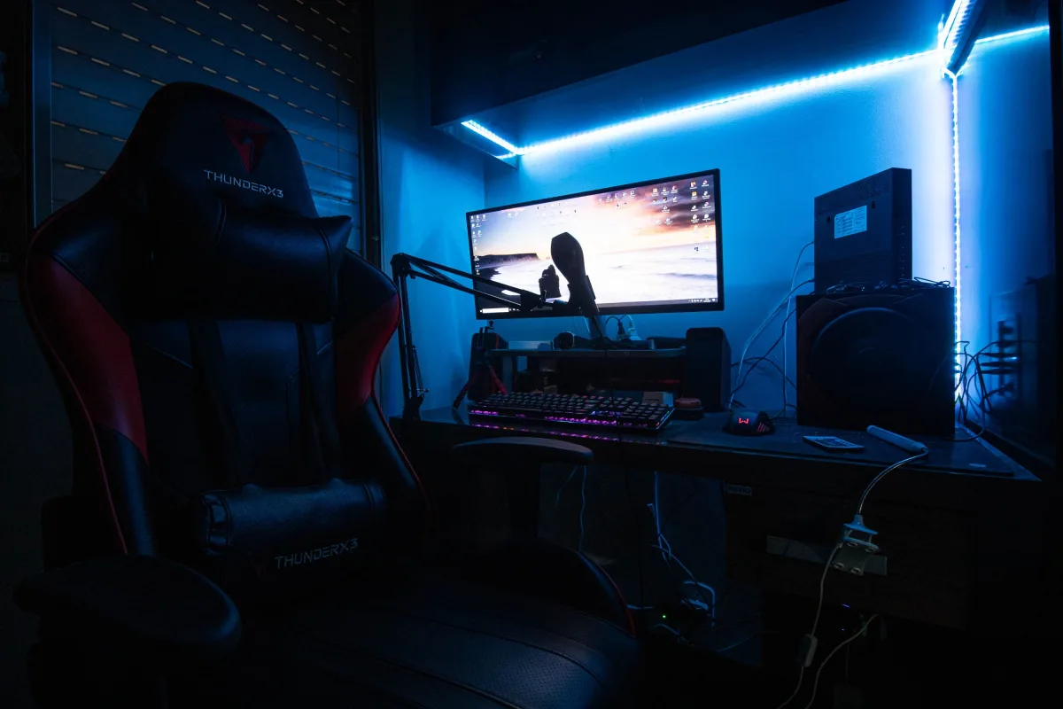 Gaming desk with dual monitors and LED lighting in a dark room
