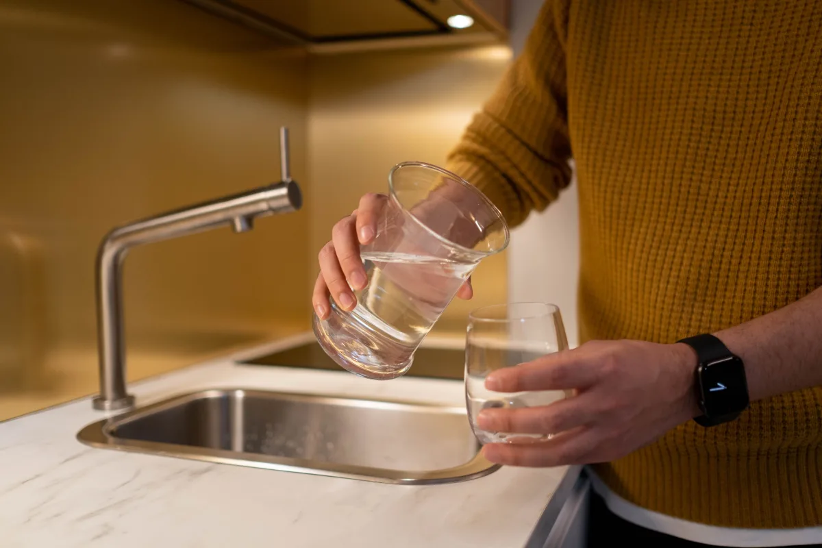 Person filling a water pitcher at a kitchen sink
