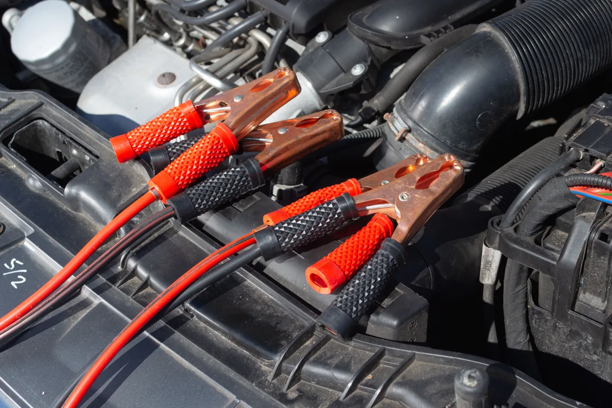 Red and black jumper cables connected to a car battery terminal