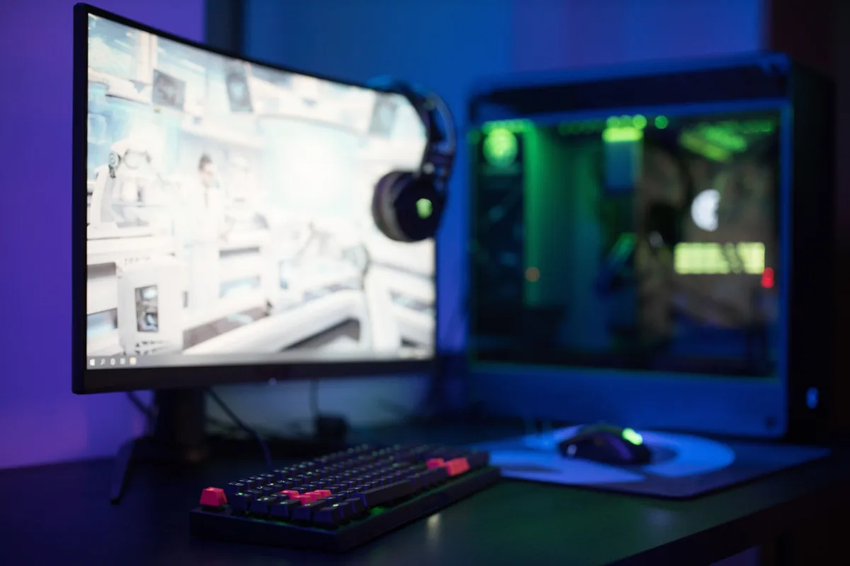 High-tech gaming setup featuring a curved monitor, RGB keyboard, and vibrant lighting