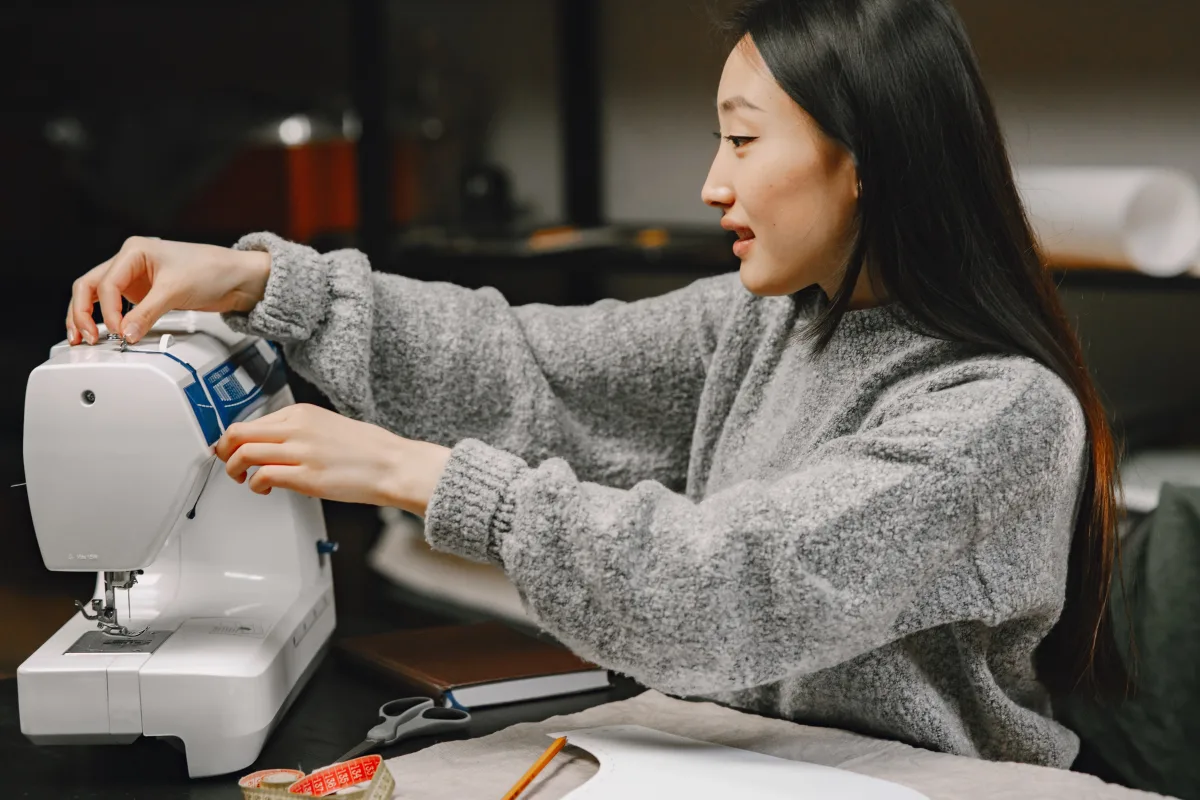 Woman sewing fabric at home on a computerized sewing machine