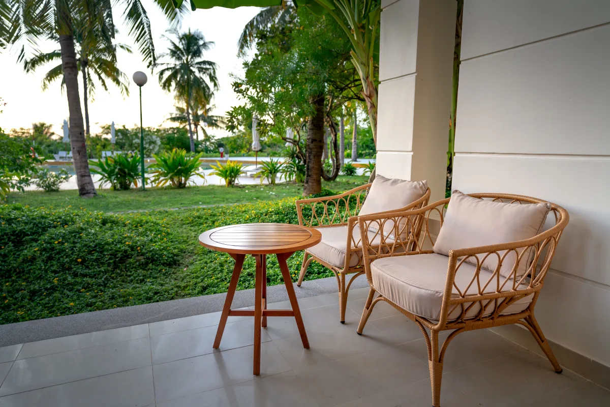 Peaceful veranda with rattan chairs and tropical plants — comparing outdoor materials