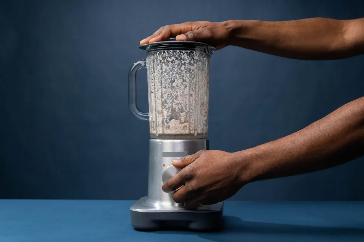 Close-up of hands operating a countertop blender in a modern kitchen
