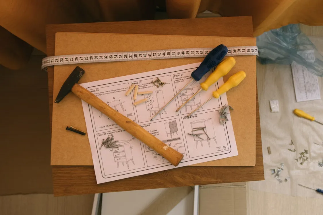 Paper assembly instructions with screwdrivers and hammer viewed from above
