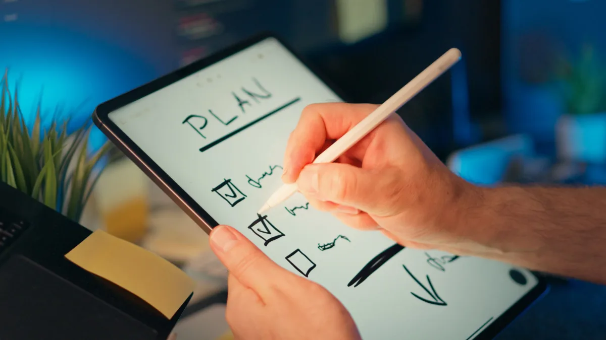 Person using tablet and stylus to plan tasks in office setting