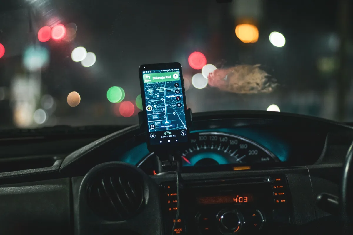 Smartphone showing Google Maps mounted on car dashboard at night