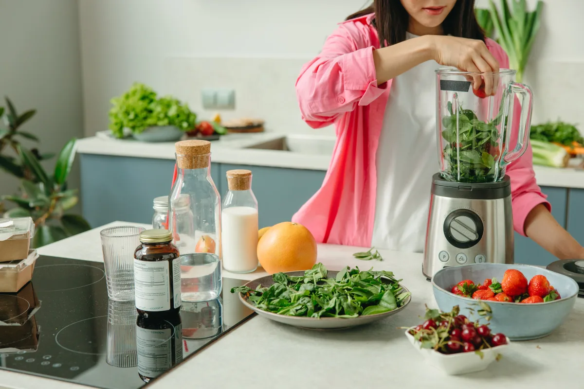 Woman blending fresh vegetables for hot soup — variable speed dial set to low