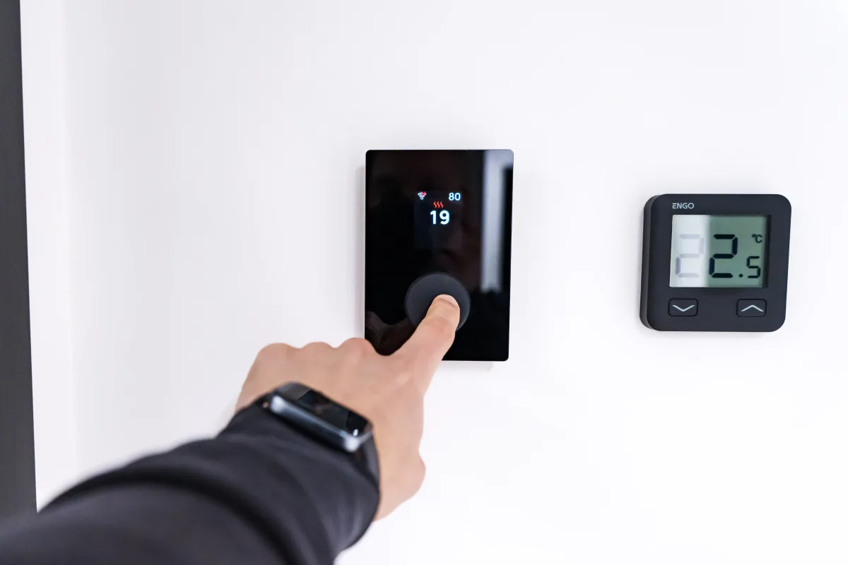 Close-up of a hand adjusting a digital smart thermostat display