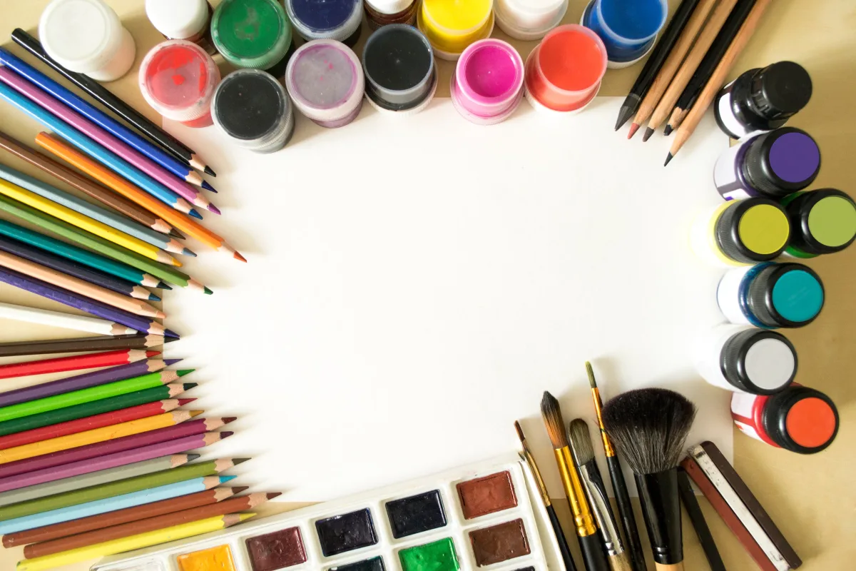 Colorful art supplies including paint tubes, pencils, and brushes on white background