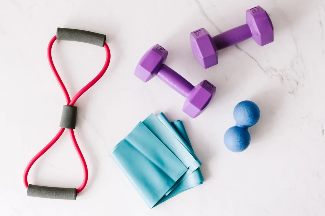 Colorful resistance bands and fitness equipment laid flat on marble surface
