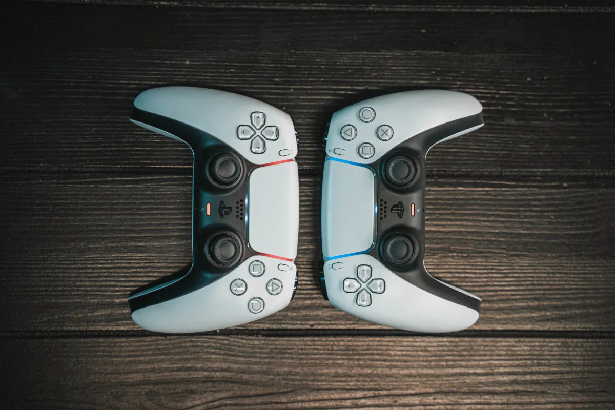 Two gaming controllers aligned symmetrically on dark wooden surface