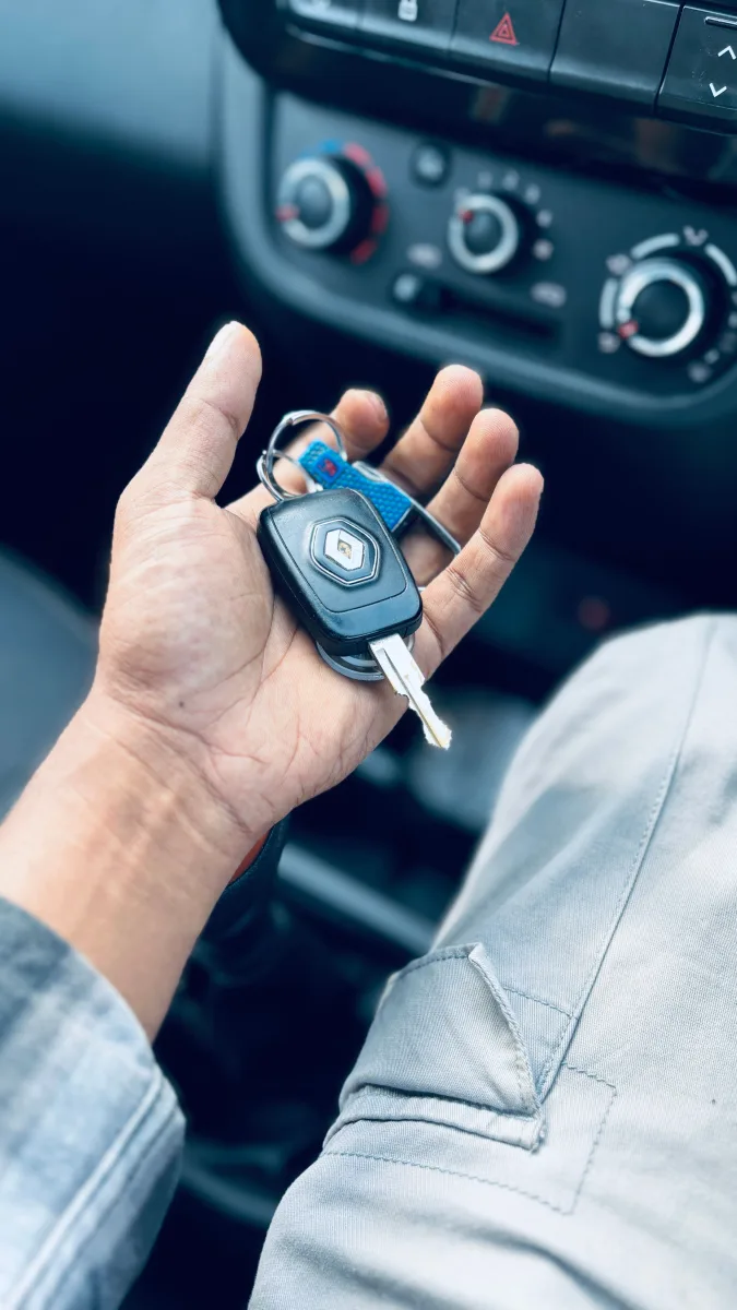Hand holding a set of keys with small tracker tag attached — bluetooth tracker concept