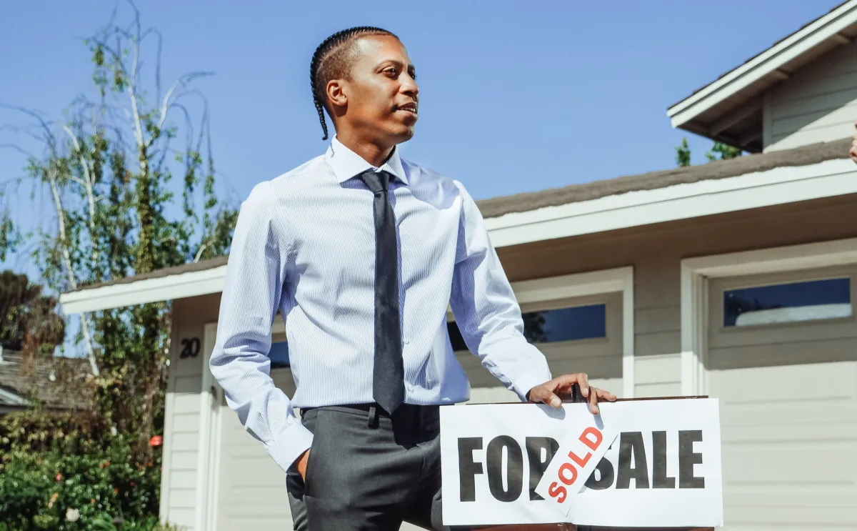 Real estate agent presenting a sold sign outside a residential property