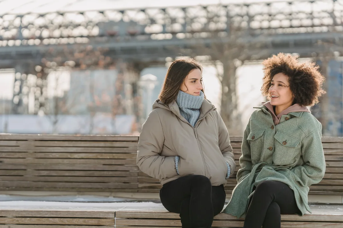 Friends in colorful winter coats sitting outdoors