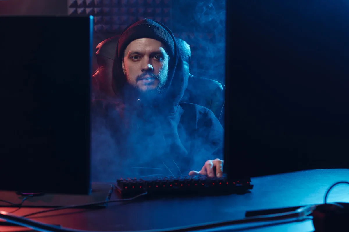 Person in dark room working at computer with dramatic lighting