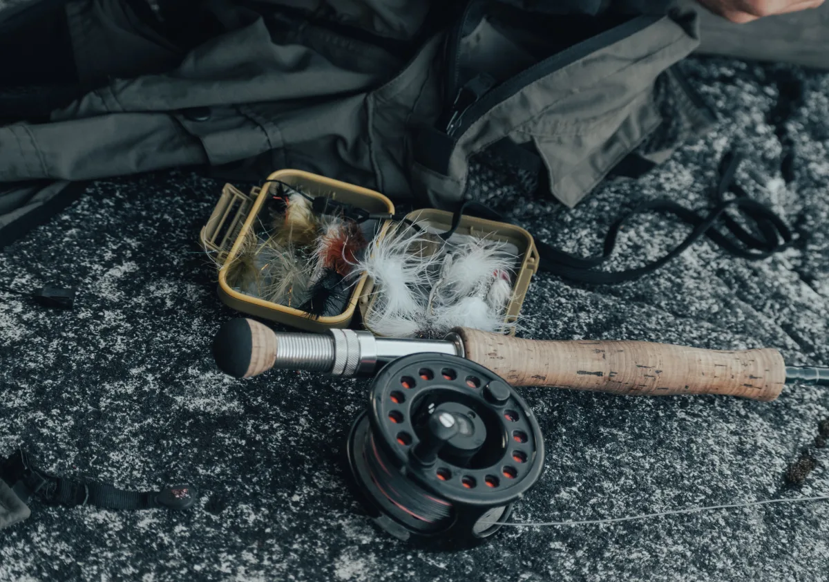 Close-up of fly fishing rod, reel, and fly lures box outdoors
