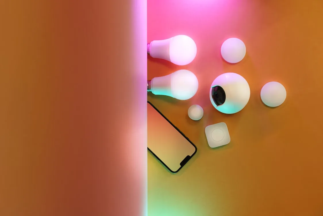 Flat lay of smart LED bulbs and smart home devices on bright background