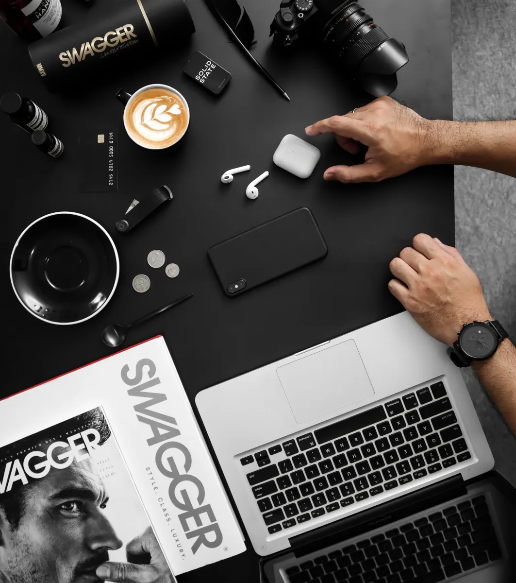 Top view flat lay of tech gadgets including smartphone and wireless earbuds on desk