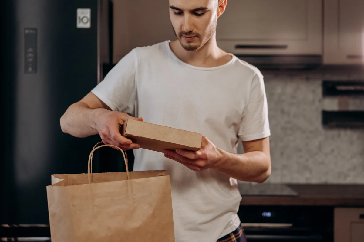 Young man in a modern kitchen unpacking a meal kit delivery package
