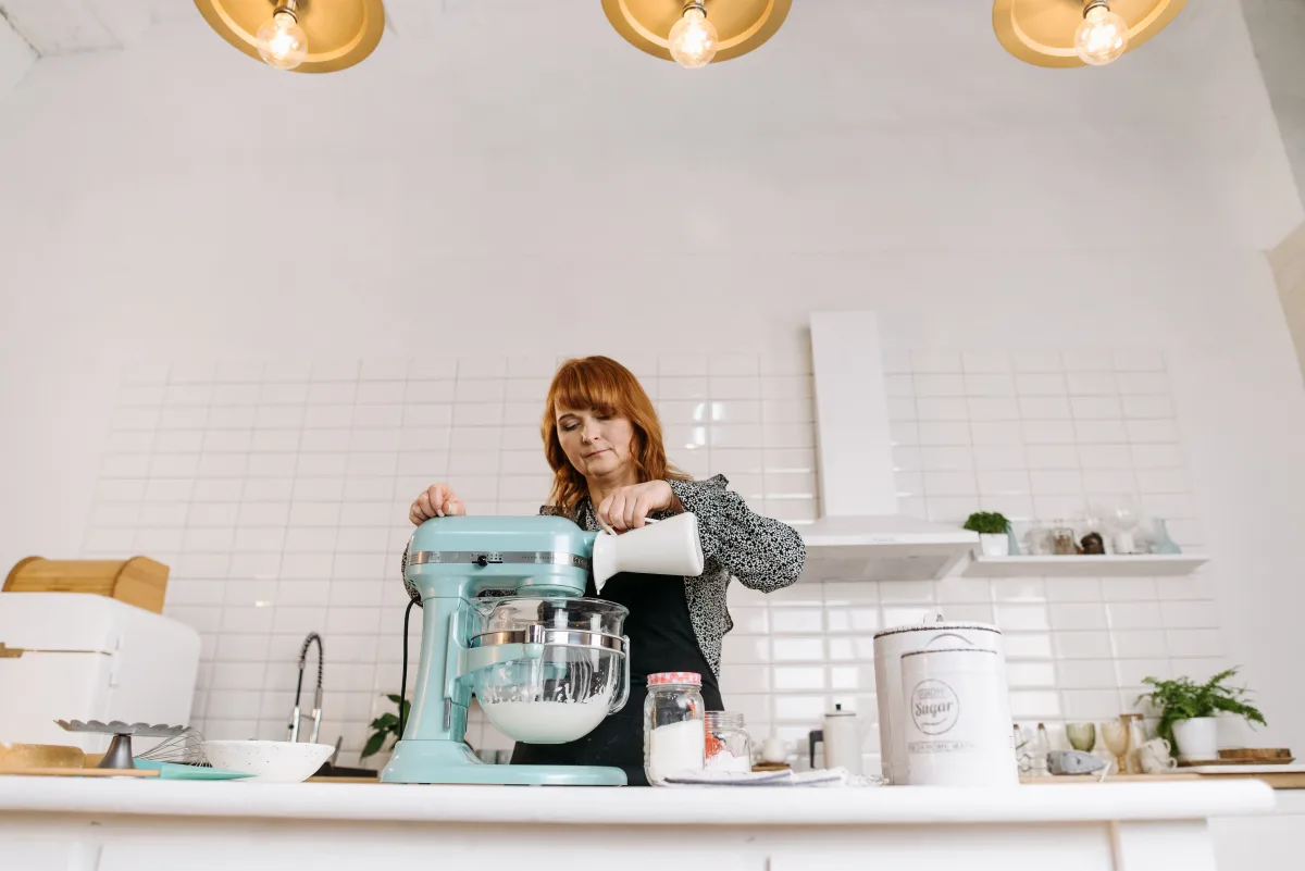 Woman pouring milk into a stand mixer bowl while baking