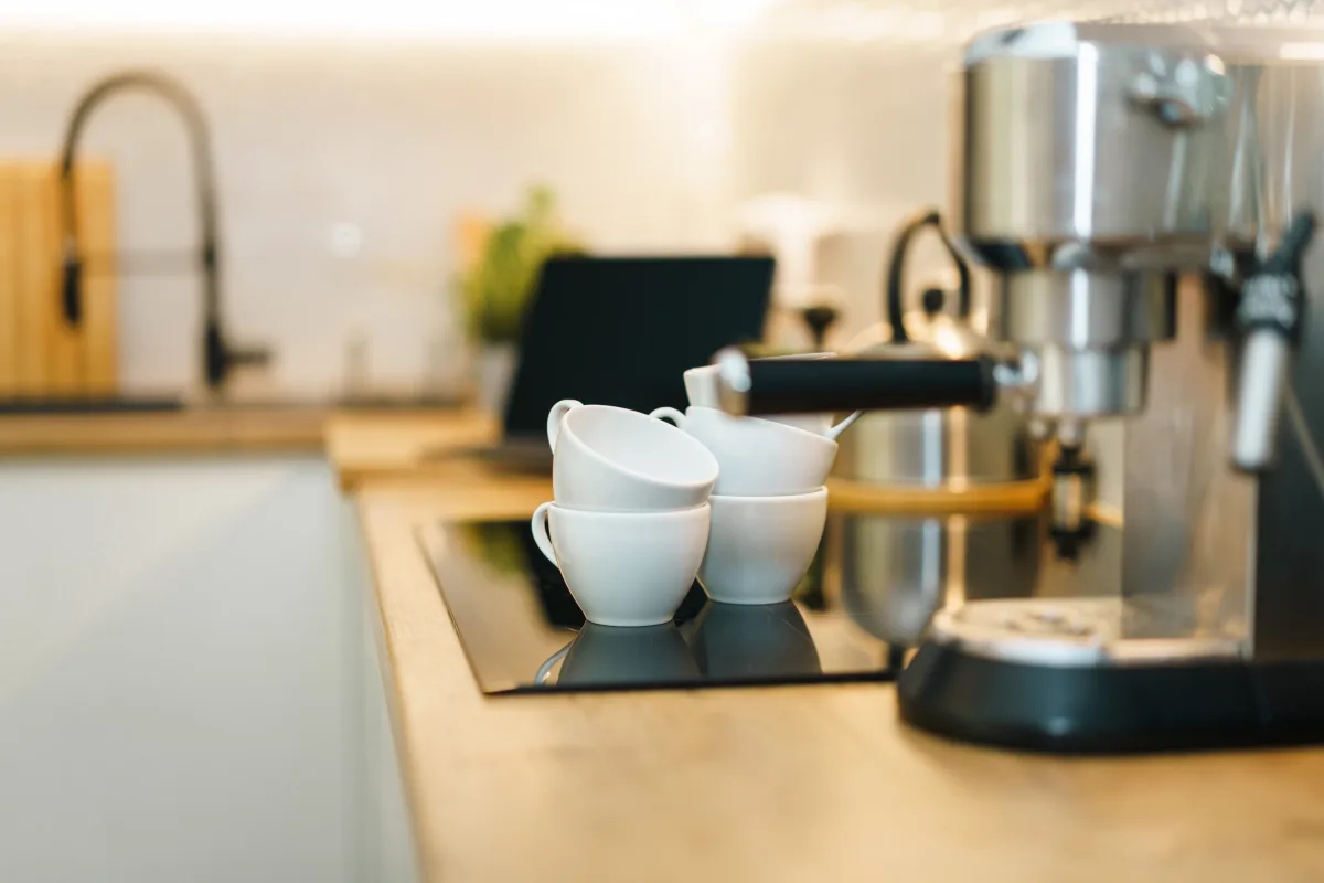 Modern espresso machine with coffee cups on a kitchen counter — drip pod and espresso comparison 2026