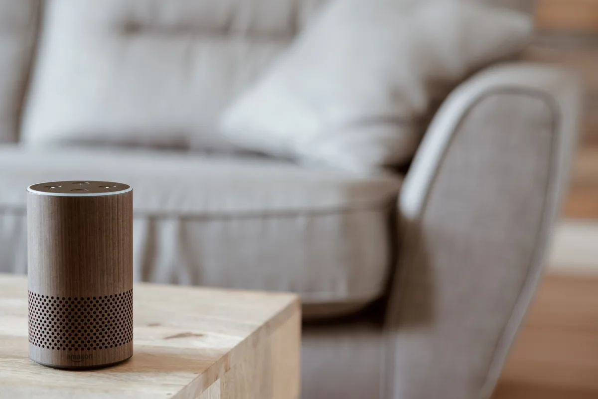 Amazon Echo smart speaker on a wooden table in a cozy minimalist living room — best Alexa smart speaker 2026