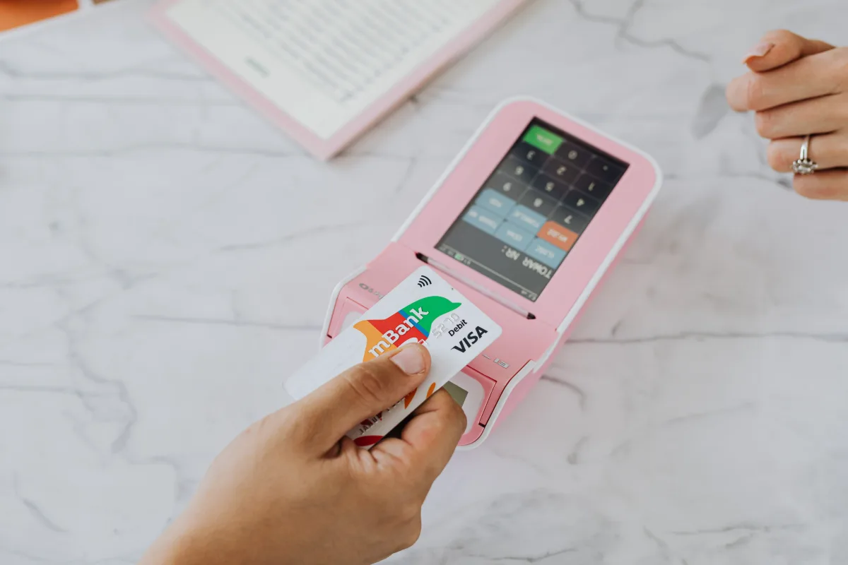 Hand using contactless card on pink POS terminal