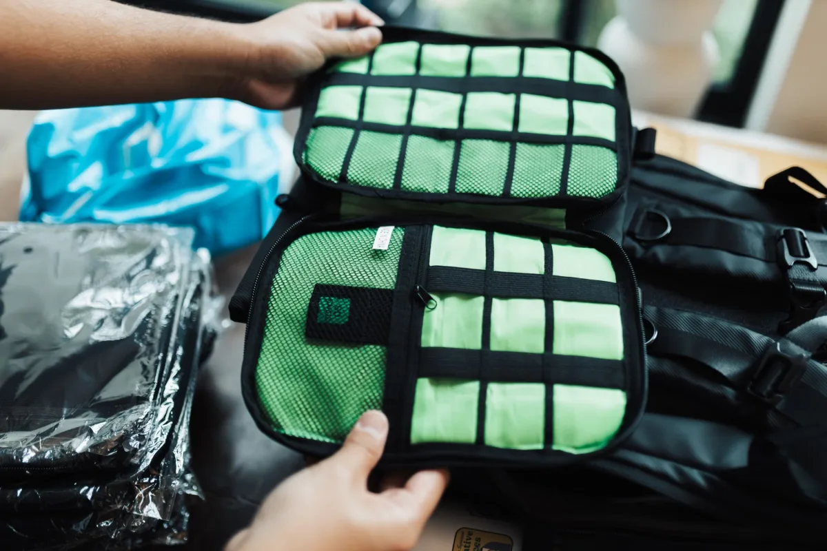 Hands organizing clothes into packing cubes inside an open travel backpack