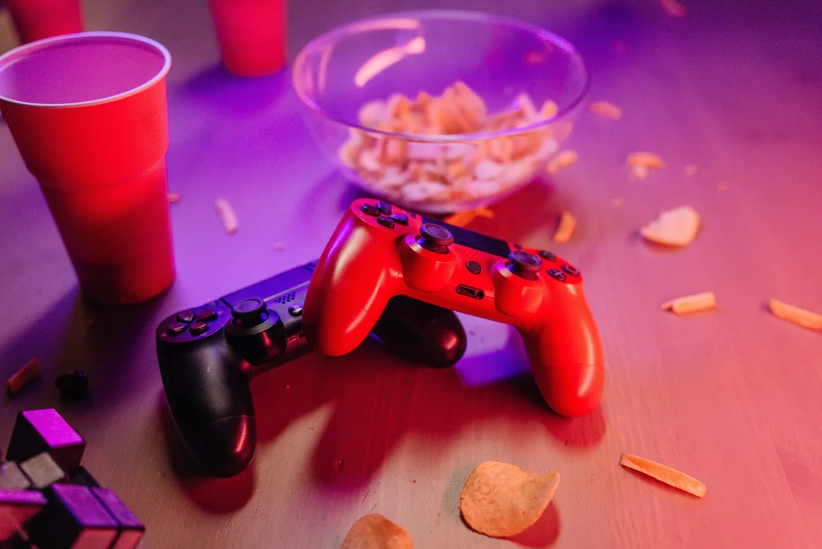 Gaming setup featuring multiple controllers, snacks, and neon lighting