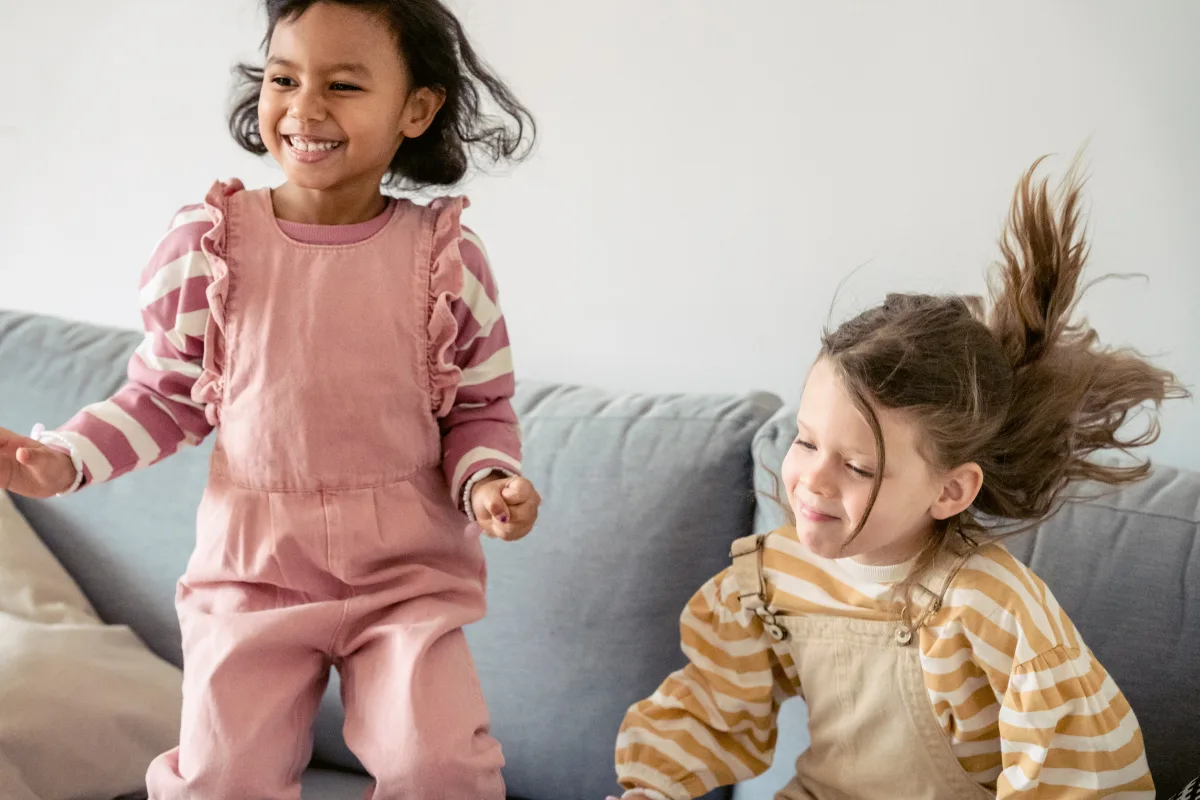 Kids in casual clothes playing and jumping on a sofa