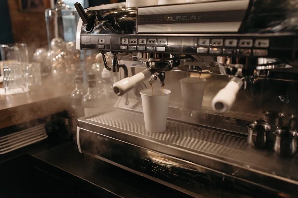 Person using a modern espresso machine at a cozy cafe — choosing the right coffee maker for your lifestyle