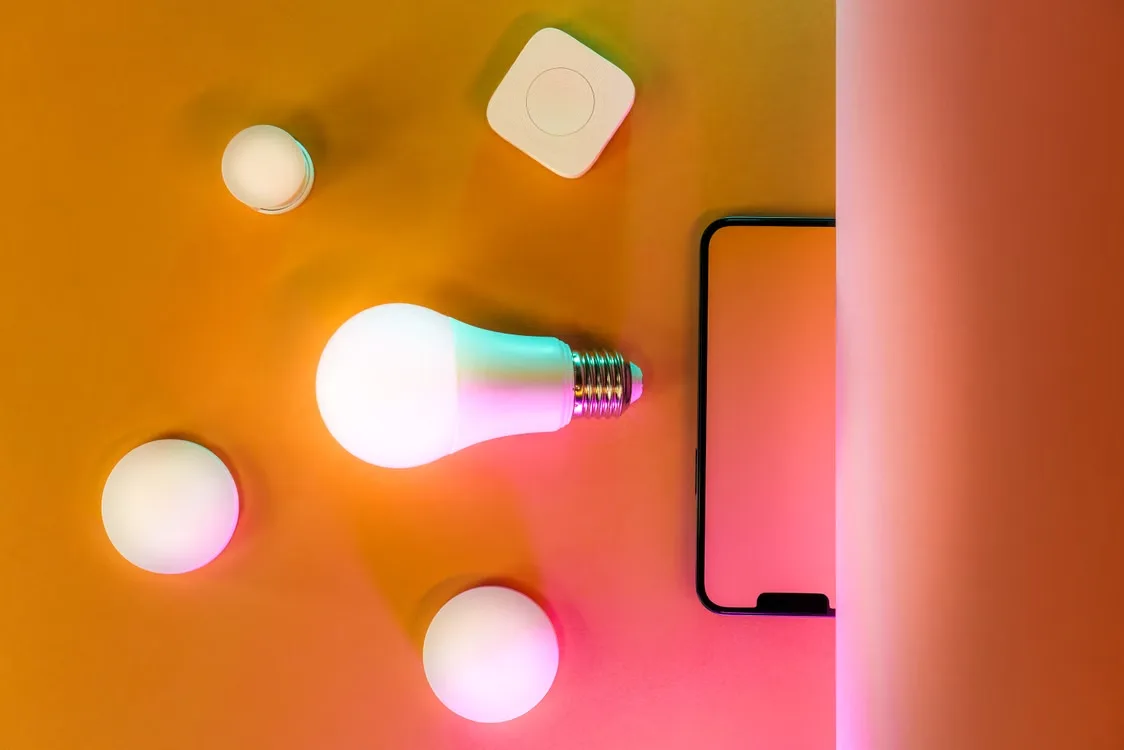 Modern smart home lighting setup featuring a glowing LED bulb on orange background