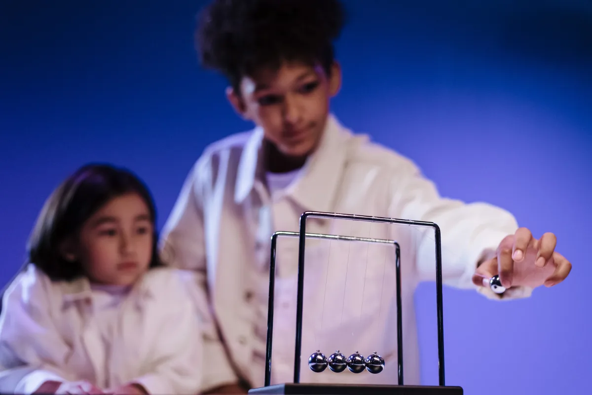 Children learning physics hands-on with Newton's Cradle — STEM toy categories science math 2026