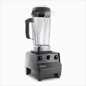Vitamix VX1 blender making a green smoothie on a white kitchen countertop