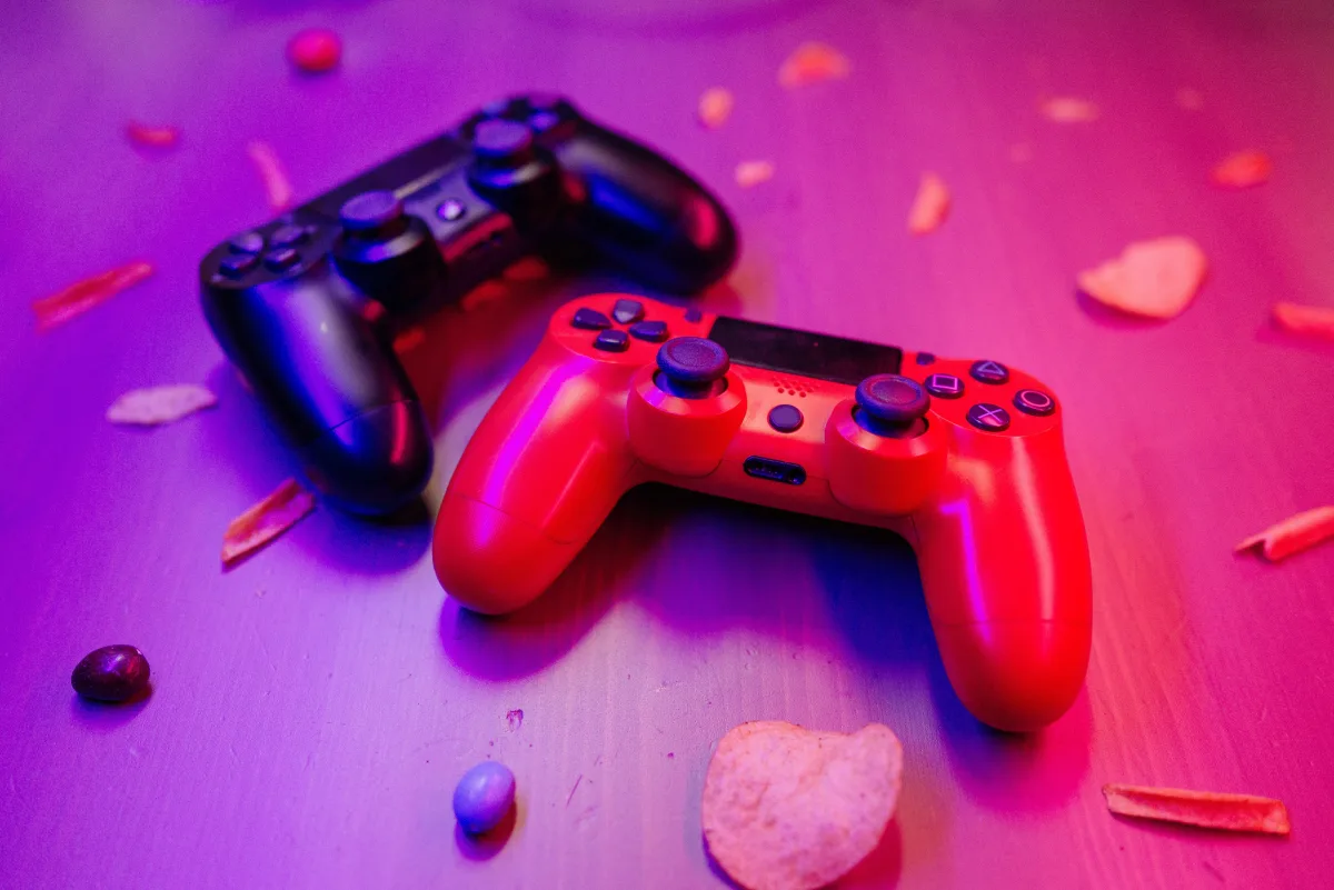 Red and black gaming controllers on a table with ambient colored lighting