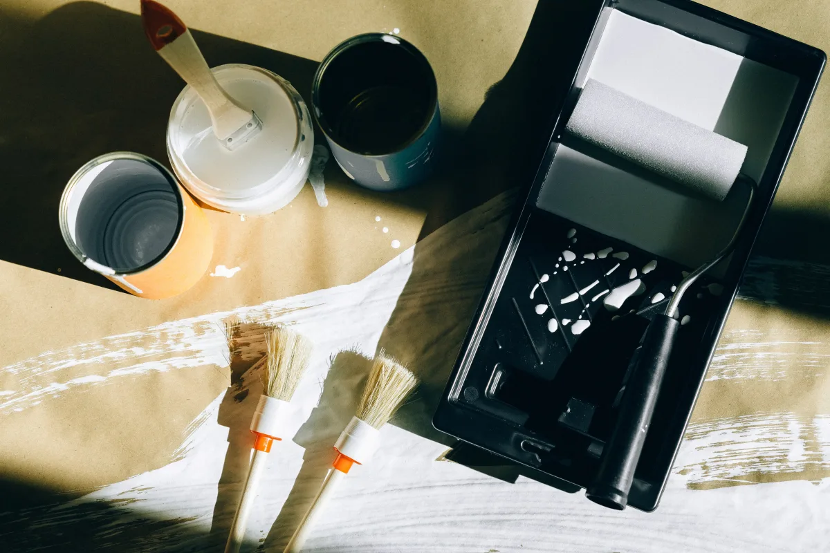 Top view of paint brushes, rollers, and paint cans on drop cloth
