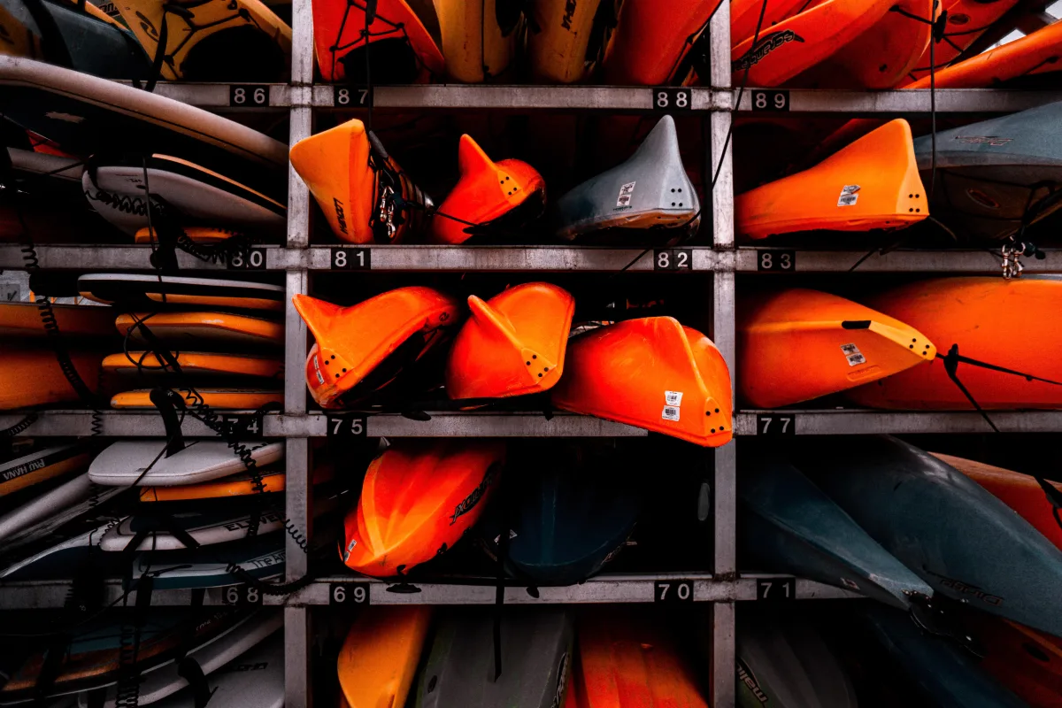 Colorful stacked kayaks in an outdoor storage rack