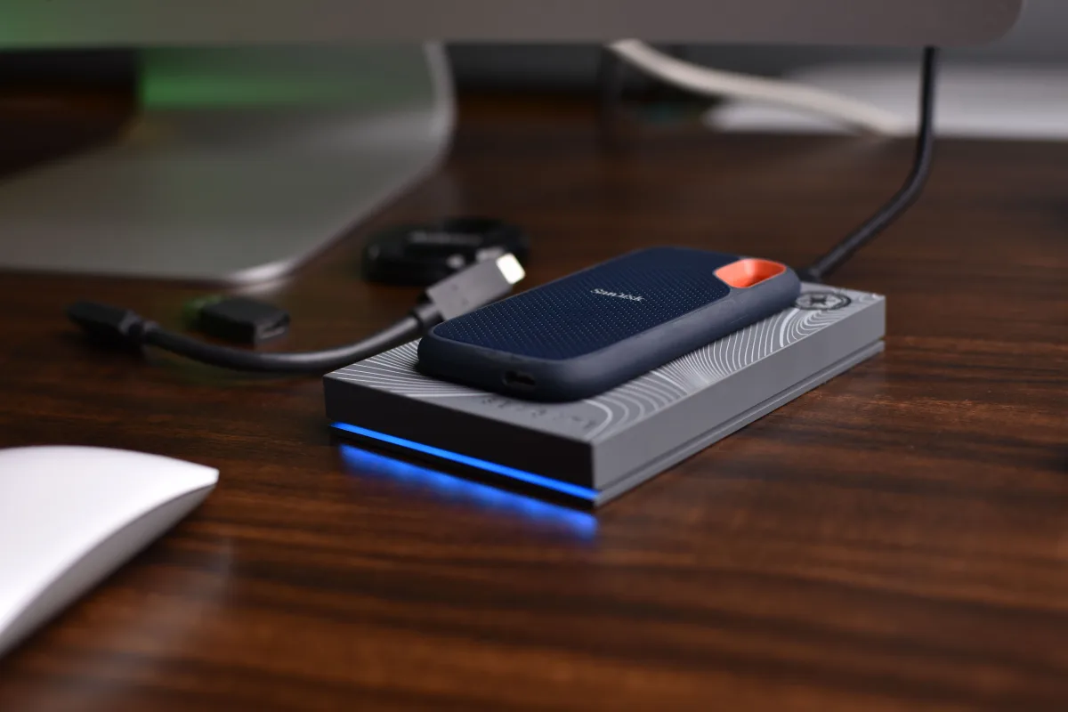 Portable USB SSD on a wooden desk with connected cables