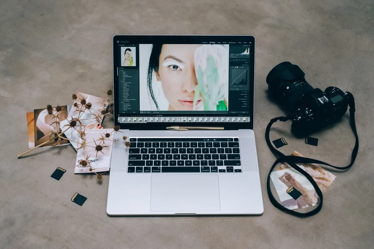 Professional photographer editing photos on laptop with camera and SD cards nearby