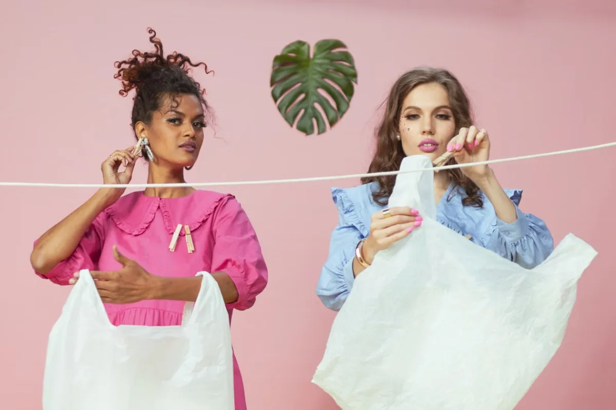 Two women hanging recycled plastic bags on a clothesline — circular fashion concept