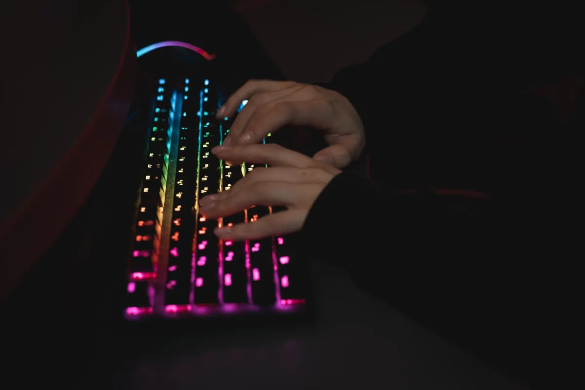 Close-up of hands typing on a backlit mechanical keyboard