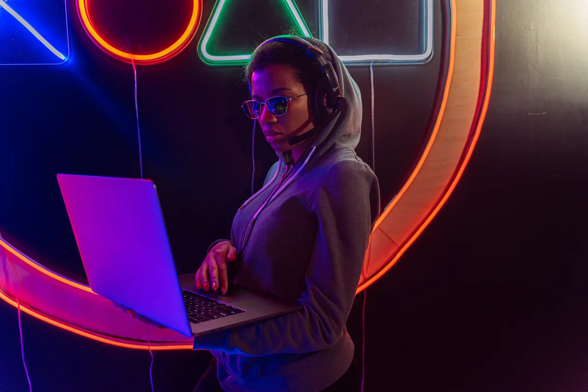 Woman with headset using a gaming laptop against a neon backdrop — how to choose the right gaming laptop 2026