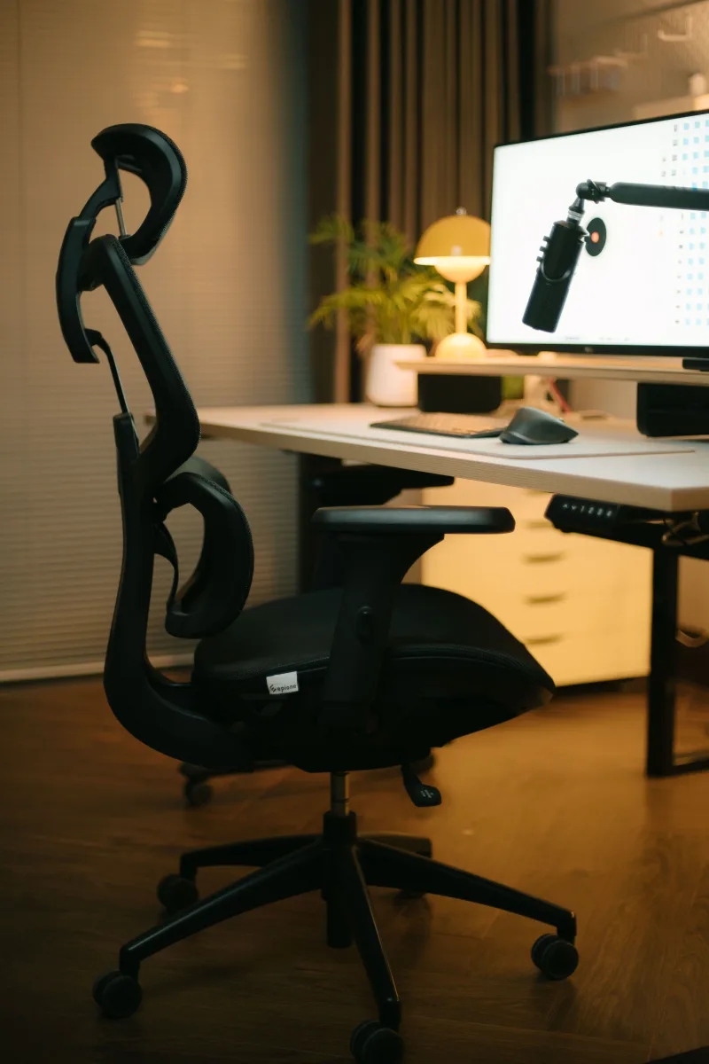Ergonomic office chair at a modern home desk setup with warm lighting