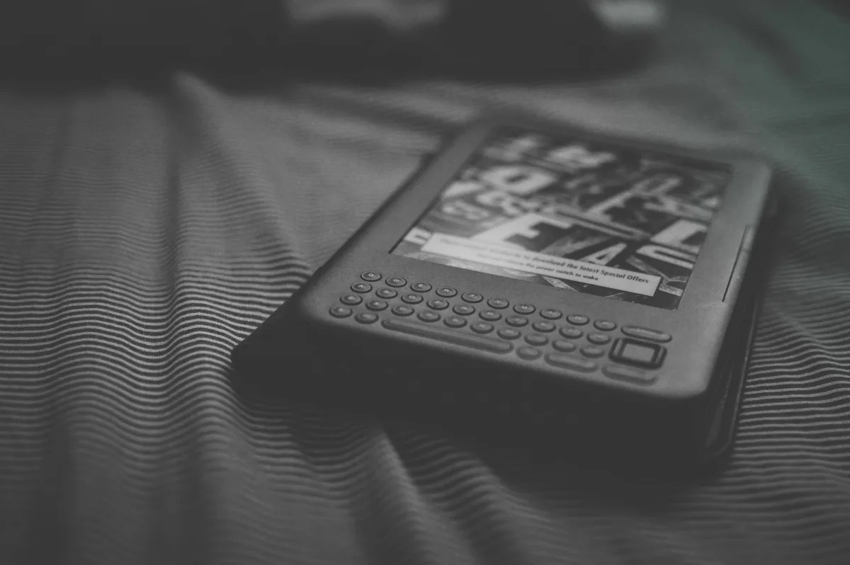 Black and white e-reader resting on patterned bedding