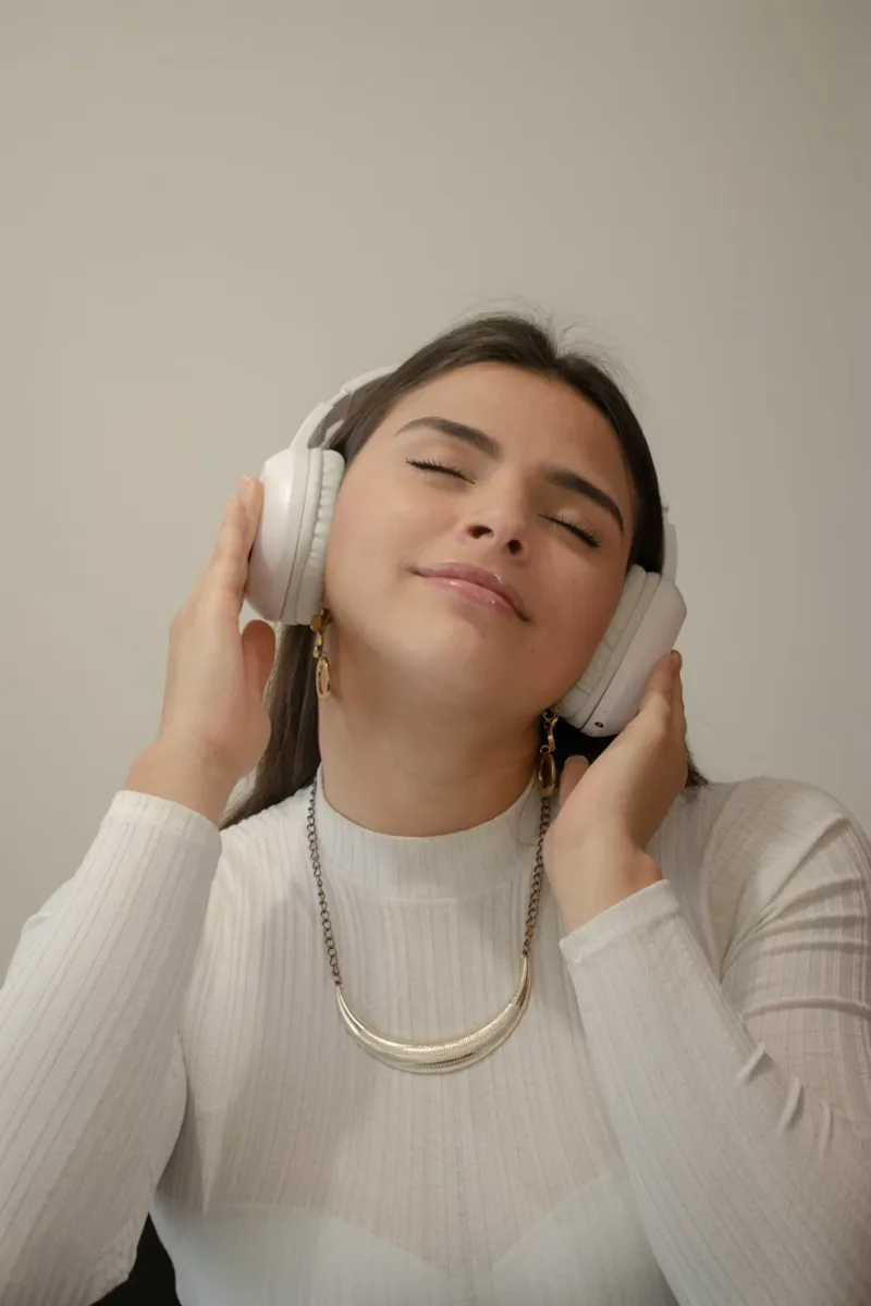 Woman listening to music with headphones, eyes closed, enjoying audio experience