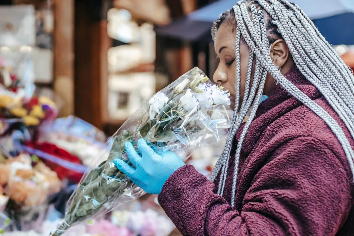 African American woman with dreadlocks smelling fresh flowers at a street floral shop