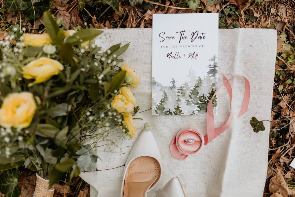 Wedding invitation styled with yellow roses, rings, and shoes