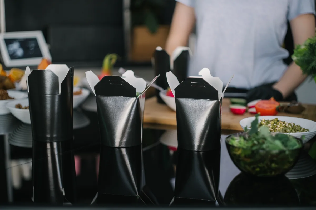 Black takeout meal boxes arranged on a contemporary kitchen counter